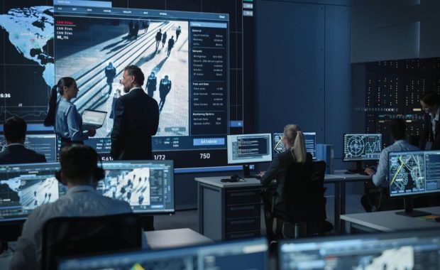 government officers discuss working matters next to a big digital screen