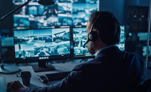 male officer works on a computer with surveillance cctv video