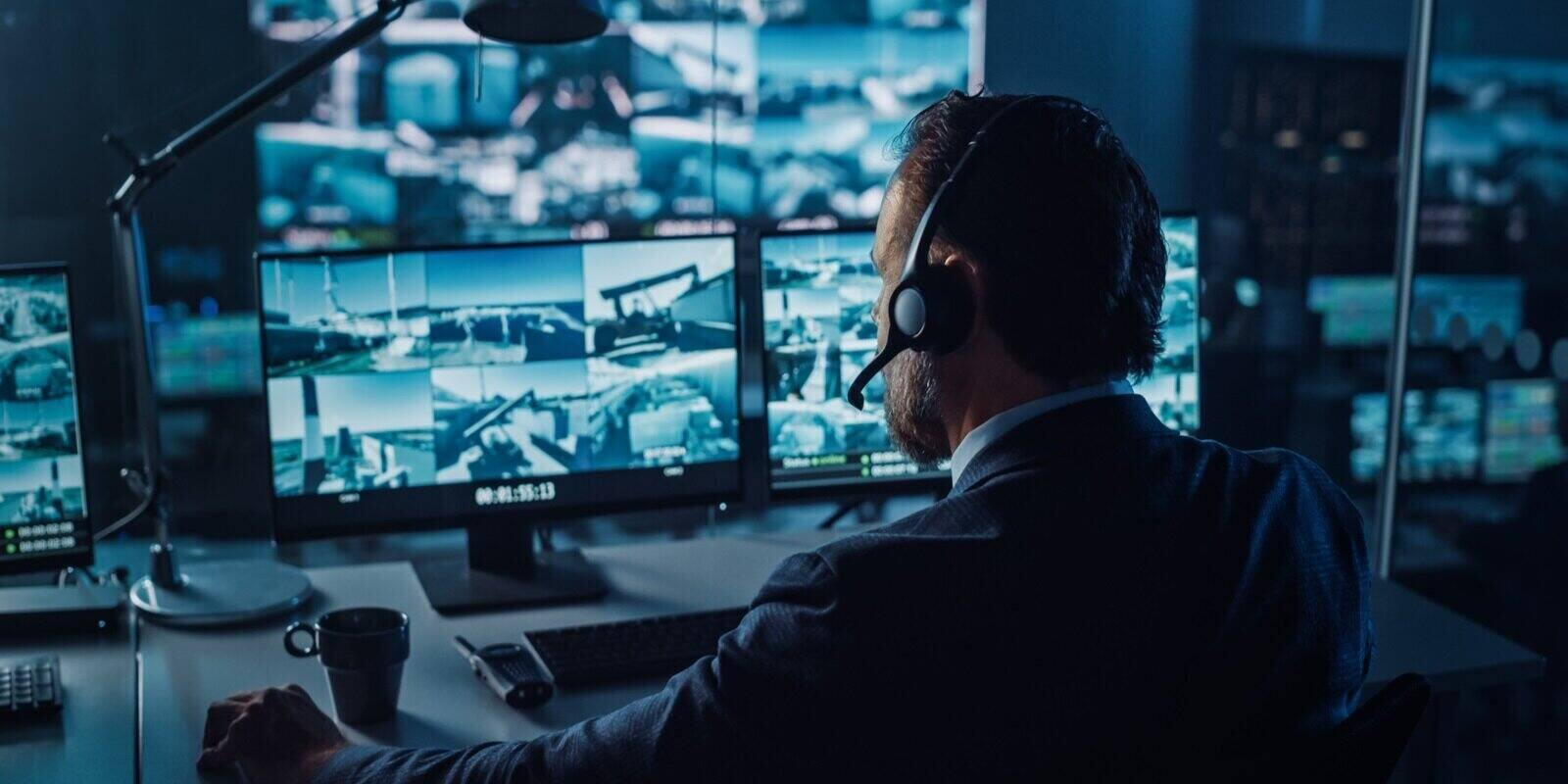 male officer works on a computer with surveillance cctv video