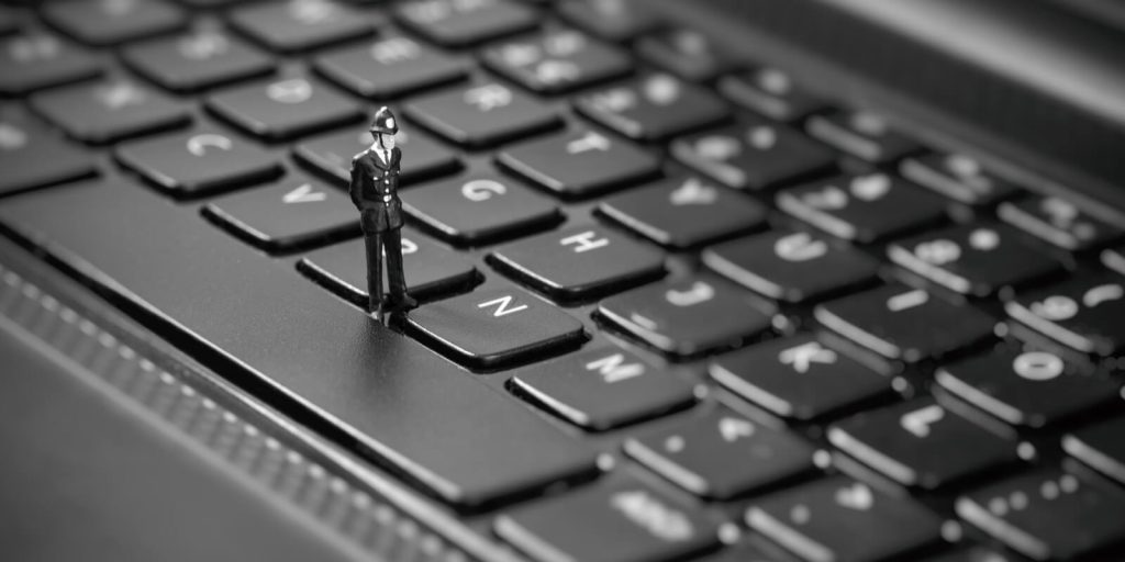 miniature policemen inspecting laptop