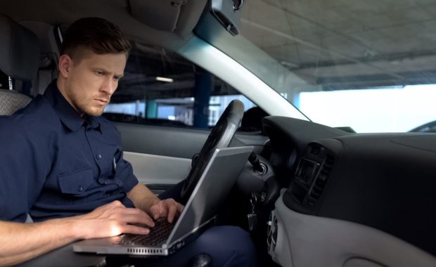 police officer working on laptop in car