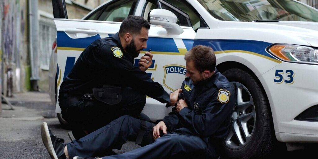 brave policeman was shoot in the shootout leaning on the police car