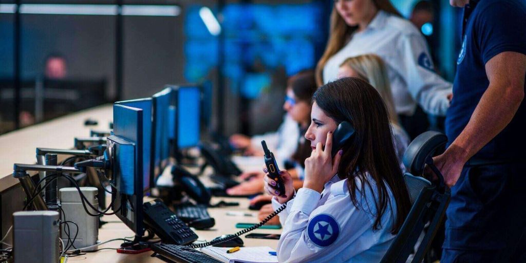 security guard with portable transmitter monitoring cameras indoors at night