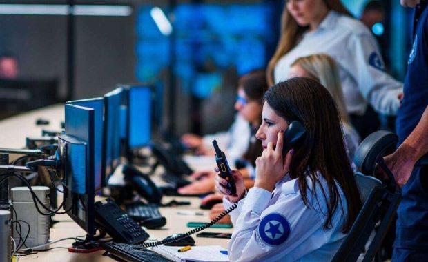 security guard with portable transmitter monitoring cameras indoors at night