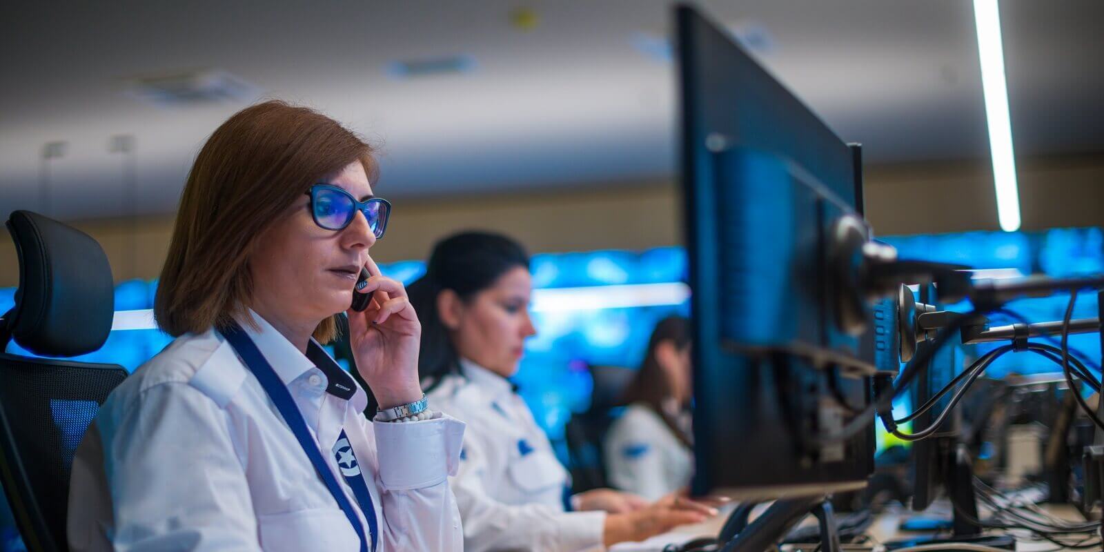 security guard sitting and monitoring modern CCTV cameras in a surveillance room