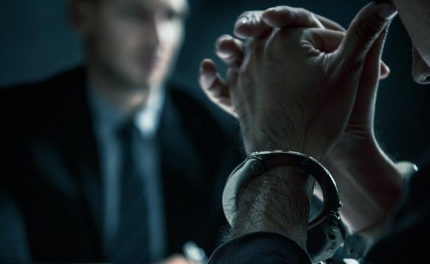 criminal man with handcuffs in interrogation room