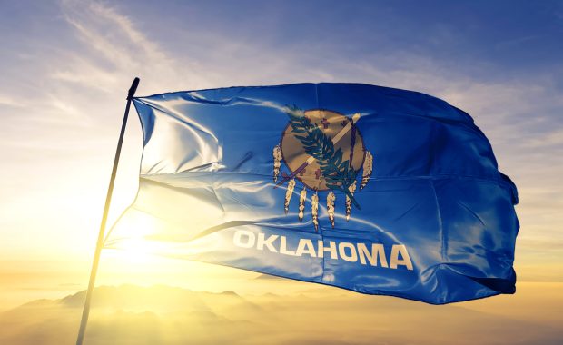 Oklahoma flag flying in front of the sunrise