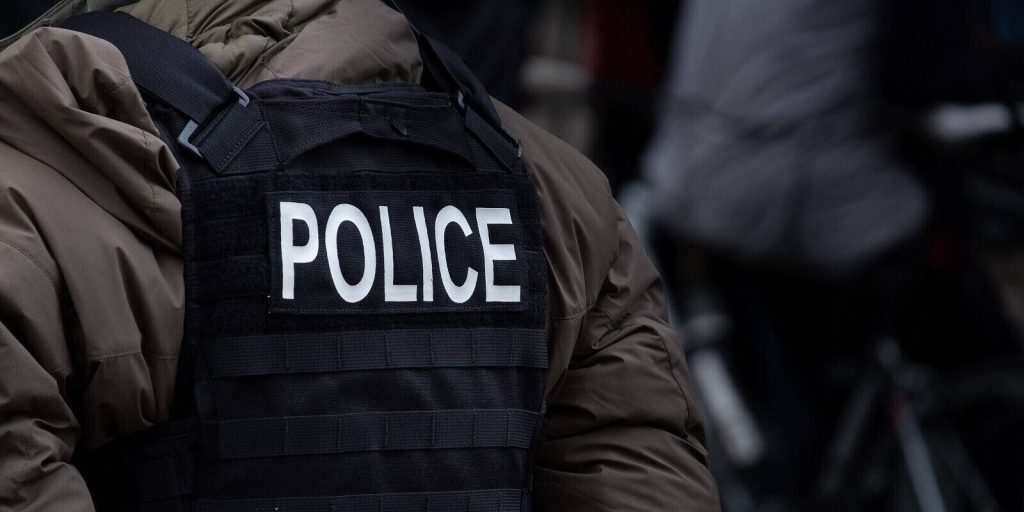 male police officer dressed in winter clothes stands back on to the camera