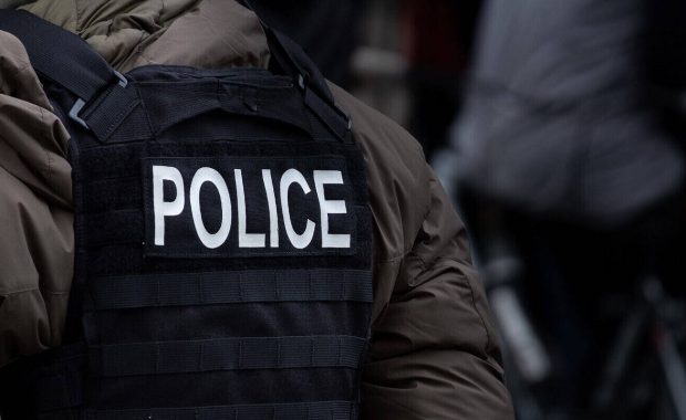 male police officer dressed in winter clothes stands back on to the camera