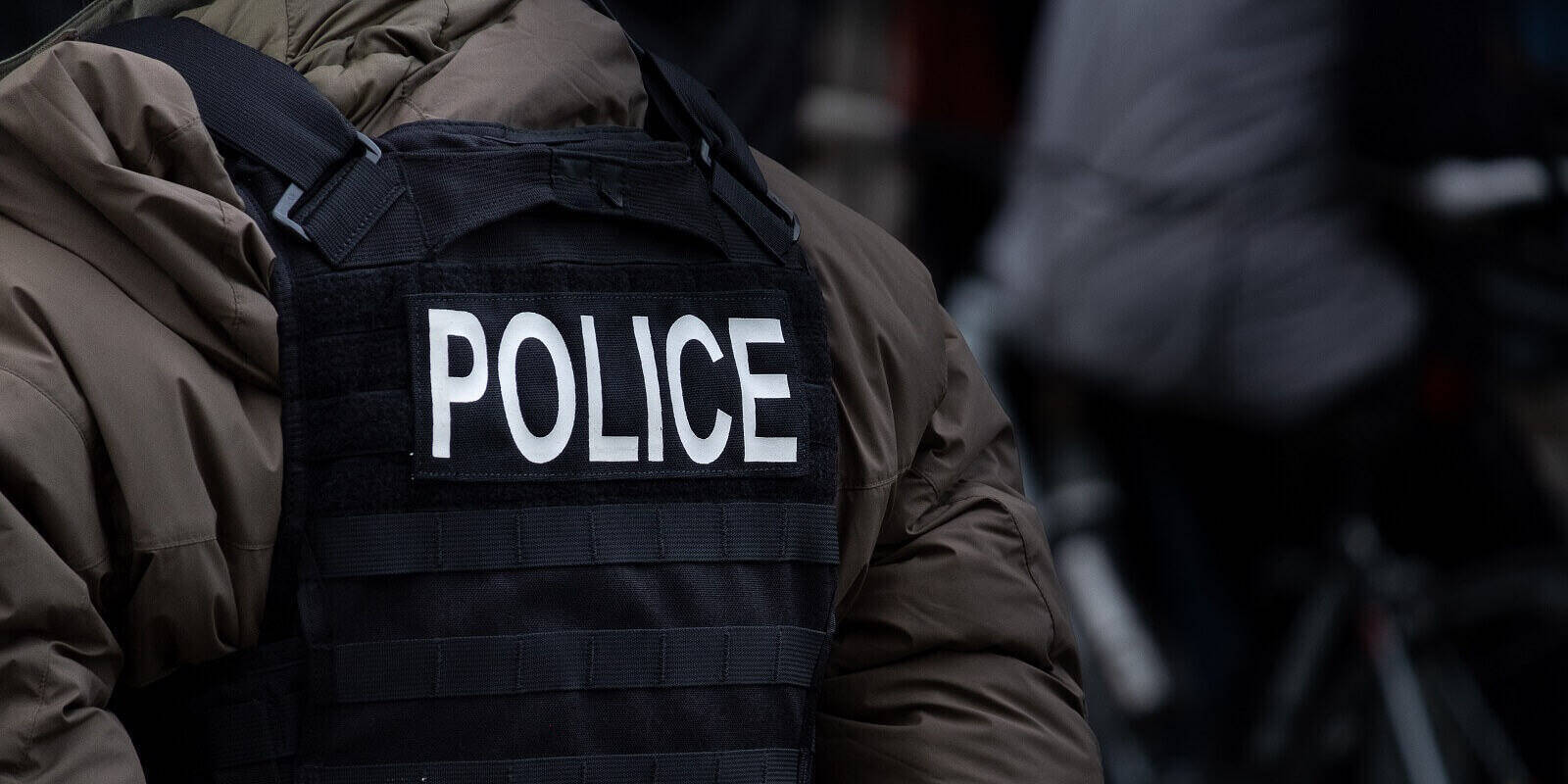 male police officer dressed in winter clothes stands back on to the camera