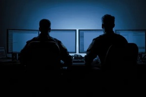 police cyber unit monitors data breaches on multiple screens in a dark environment for public safety