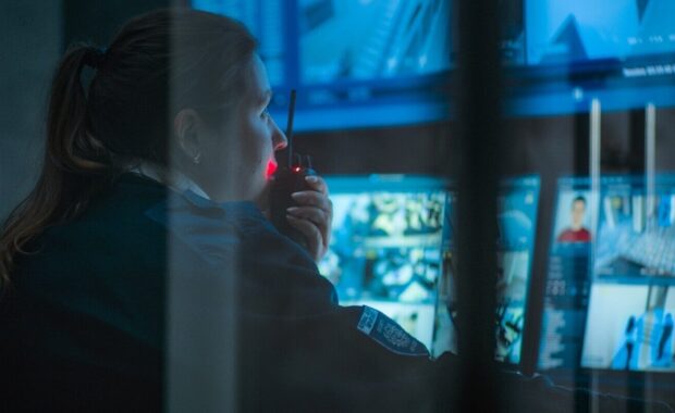 close up of female CCTV operator working on computer in monitoring center with security cameras