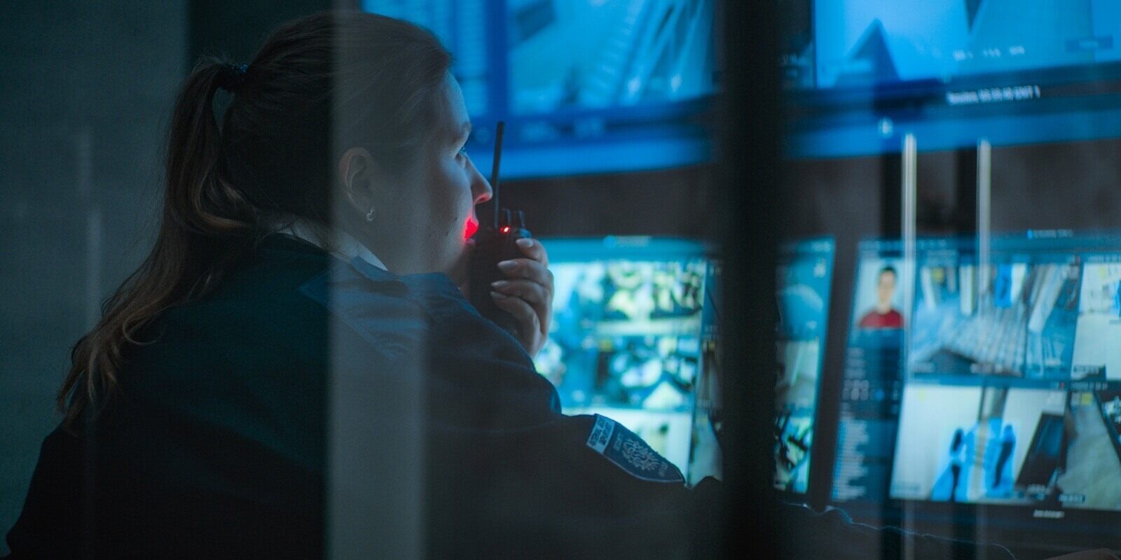 close up of female CCTV operator working on computer in monitoring center with security cameras