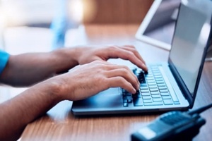 laptop, radio and hands of security typing or writing an investigation project at a law enforcement office