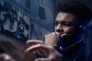 male operator in headset talk with colleague and monitor CCTV cameras