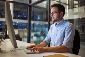 Businessman, computer and night office work for digital programmer, cybersecurity and software design. Thinking web design engineer, developer and worker with technology for ux seo or database coding.