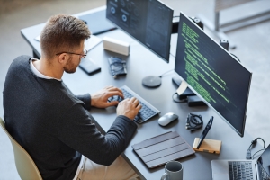 High angle view at software developer writing code while using computer and data systems in office