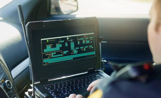 database, laptop and a police officer in a car for security, urban law and safety data while working