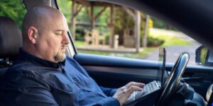 happy businessman sitting in the car and talking on the tablet during a break