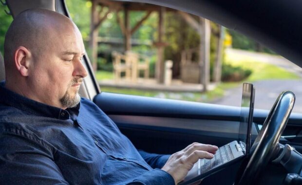 happy businessman sitting in the car and talking on the tablet during a break