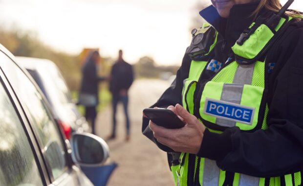 female traffic police officer recording details of road traffic accident
