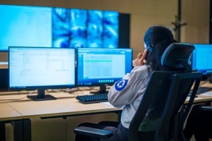 female security guard sitting back and monitoring modern CCTV cameras in a surveillance room