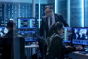 team of government agents tracking fugitive with boss's survillance in big monitoring room